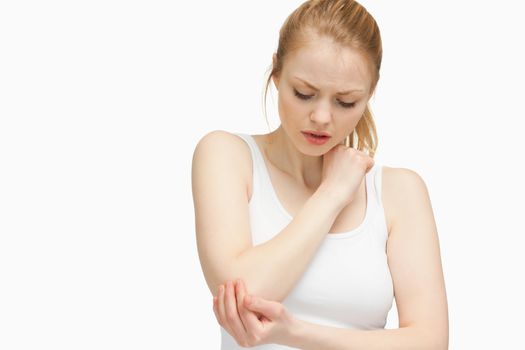 Young woman touching her elbow against white background