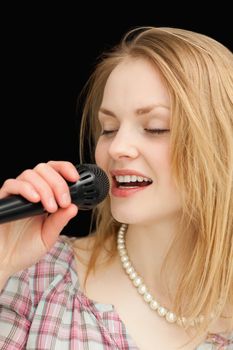 Woman singing while closing her eyes against black background