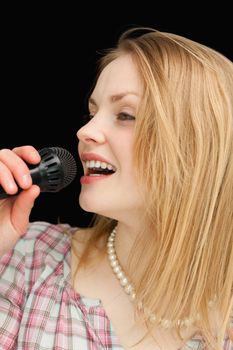 Blonde-haired woman singing against black background