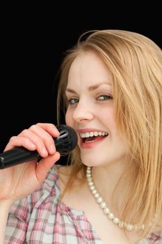 Fair-haired woman singing against black background