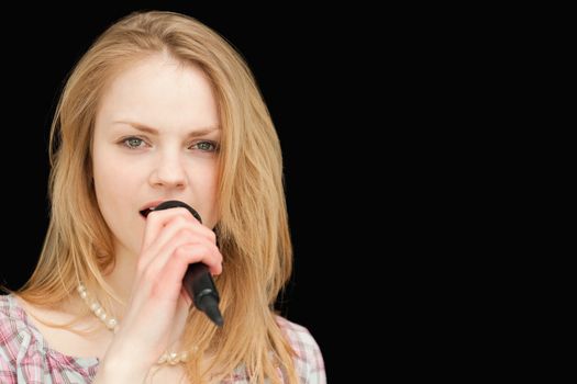 Young blonde-haired woman singing against white background