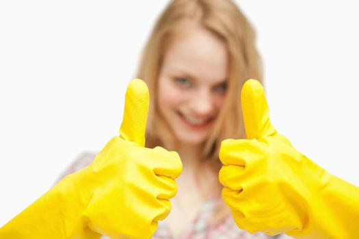Woman thumbs up while wearing cleaning gloves against white background