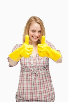 Young woman wearing cleaning gloves while thumbs up against white background