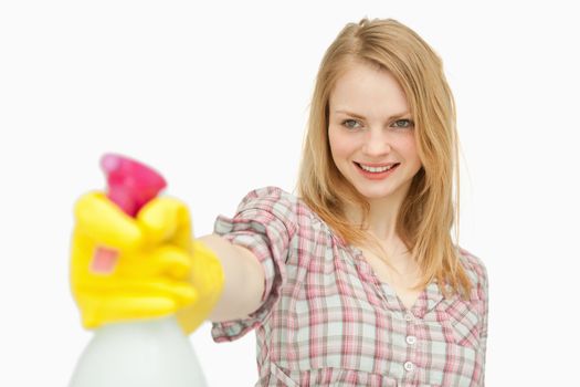 Woman holding a spray bottle while smiling against white background