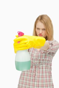 Young woman holding a spray bottle against white background