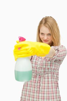 Young woman smiling while holding a spray bottle against white background