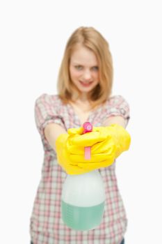 fair-haired woman holding a spray bottle against white background