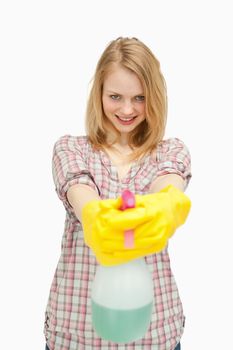 Smiling woman holding a spray bottle against white background