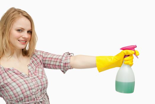 Smiling young woman holding a spray bottle against white background