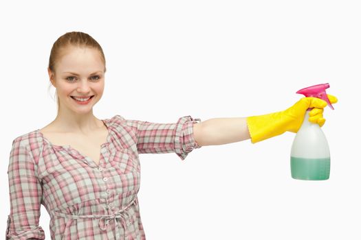 Cheerful woman holding a spray bottle against white background