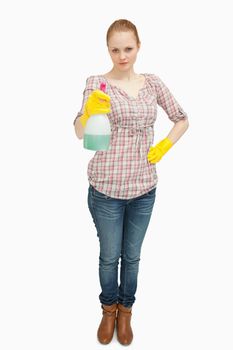 Woman standing while holding a spray bottle against white background