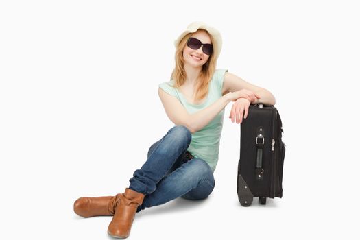 Woman sitting next to a suitcase against white background