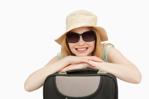 Cheerful woman leaning on a suitcase against white background