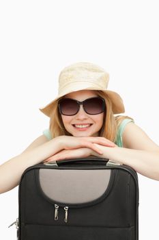 Close up of a smiling woman leaning on a suitcase against white background