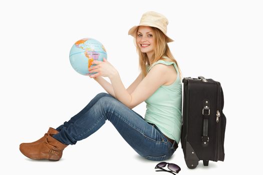 Woman smiling while holding a world globe against white background