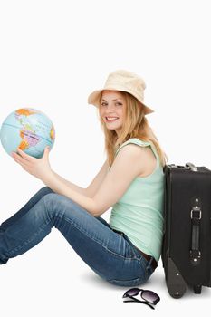 Young woman smiling while holding a world globe against white background