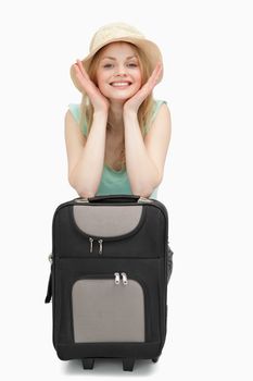 Smiling woman leaning on a suitcase while sitting against white background