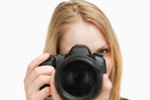 Young woman holding a camera against white background
