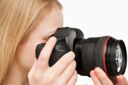 Close up of a young woman holding a camera against white background