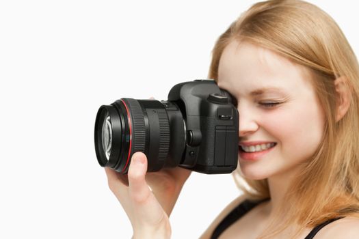 Smiling woman holding a camera against white background