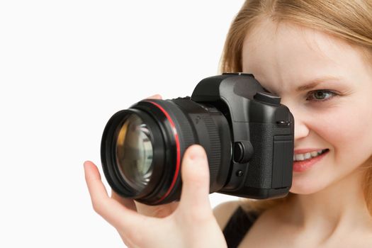 Cheerful woman shooting with a camera against white background