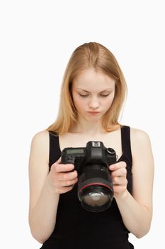 Woman looking at the screen of her camera against white background