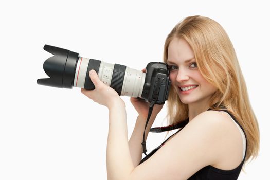 Woman looking at the camera while holding a camera against white background