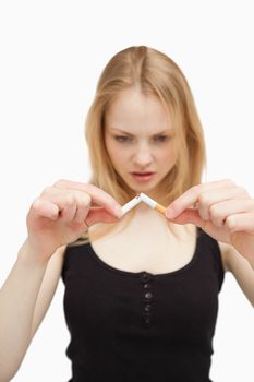 Blonde-haired woman breaking a cigarette against white background