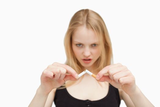 Angry woman braking a cigarette against white background