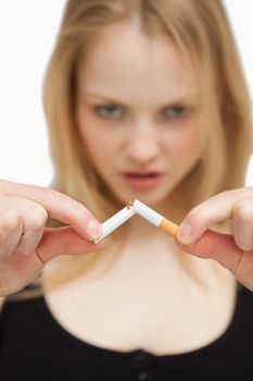 Young woman breaking a cigarette against white background