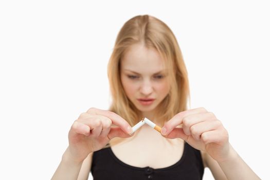 Fair-haired woman braking a cigarette against white background