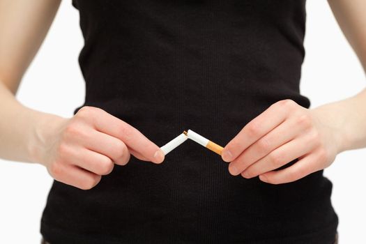 Close up of hands breaking a cigarette against white background