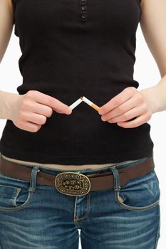 Woman breaking a cigarette with her hands against white background