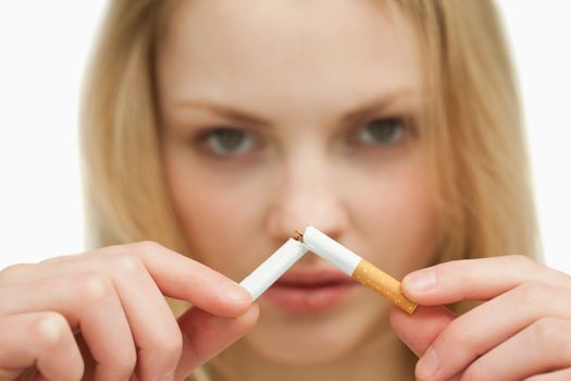 Close up of a young woman breaking a cigarette against white background