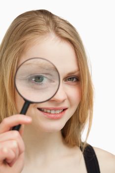 Close up of a woman using a magnifying glass against white background