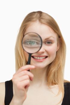 Joyful woman using a magnifying glass against white background