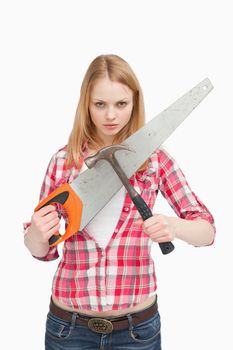 Woman holding a saw and a hammer against white background