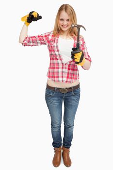 Woman standing while holding a hammer against white background