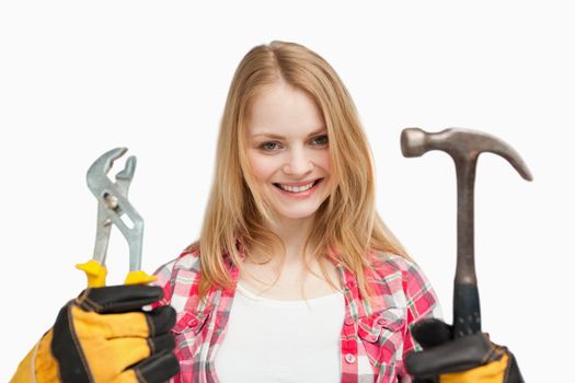 Woman holding tools while standing against white background