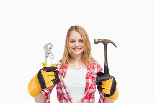 Woman holding tools while smiling against white background