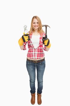 Woman standing while holding tools against white background