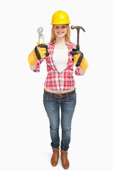 Woman wearing a safty helmet while holding tools against white background