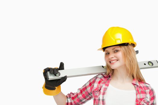 Woman smiling while holding a spirit level against white background