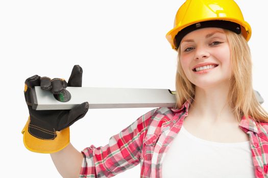 Young woman holding a spirit level against white background