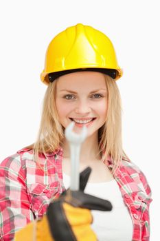 Smiling woman presenting a wrench against white background