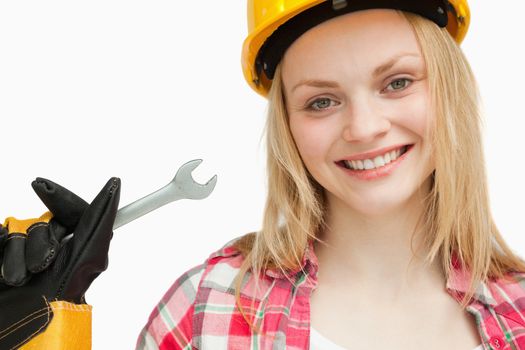 Smiling woman holding a wrench against white background