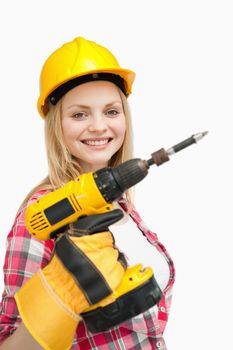 Woman smiling while holding an electric screwdriver against white background