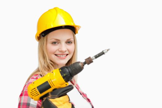 Woman holding an electric screwdriver while smiling against white background