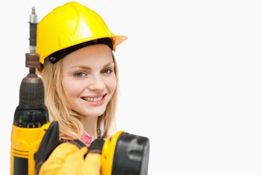 Young woman holding an electric screwdriver against white background