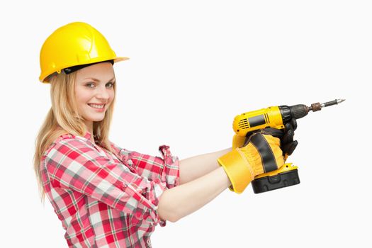 Smiling woman using an electric screwdriver against white background